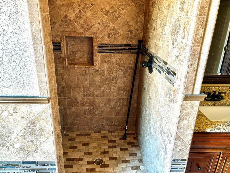 Bathroom featuring tiled shower and vanity