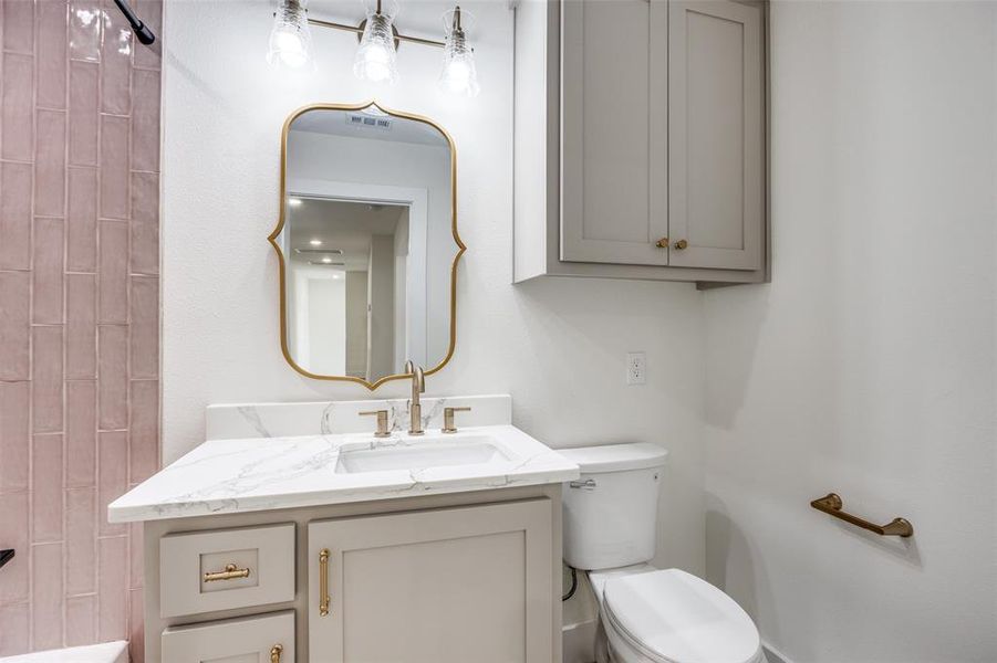 Upstairs bathroom featuring quartz vanity and tub / shower combination with decorative tile.