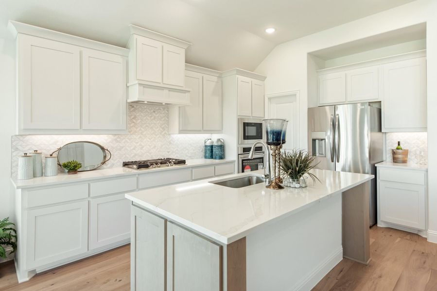 White kitchen with center island, quartz countertops, stainless steel appliances, and light wood floors White kitchen with center island, quartz countertops, stainless steel appliances, and light wood floors