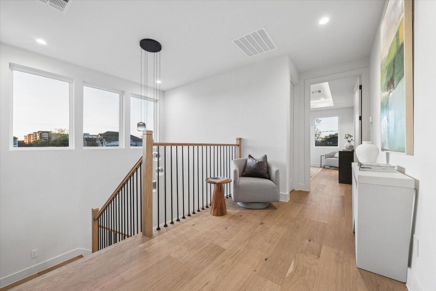 A modern six-light chandelier creates a striking focal point in the stairwell.
