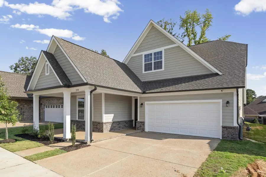 Gable roofline with shingle siding, an attached two-car garage, covered entry porch, and partial brick facade Gable roofline with shingle siding, an attached two-car garage, covered entry porch, and partial brick facade