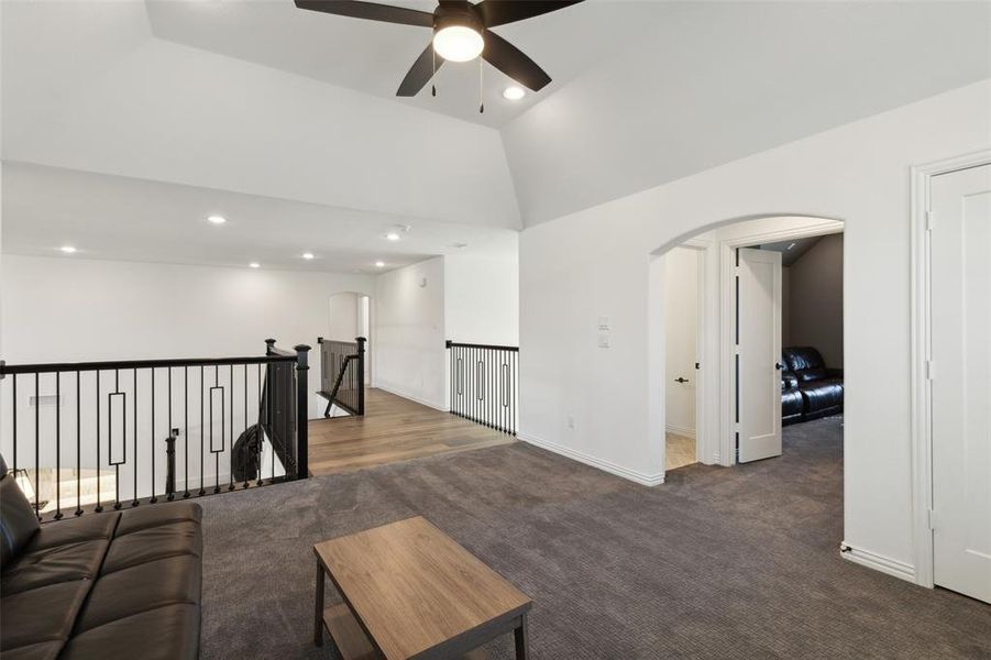 Carpeted living room with lofted ceiling and ceiling fan