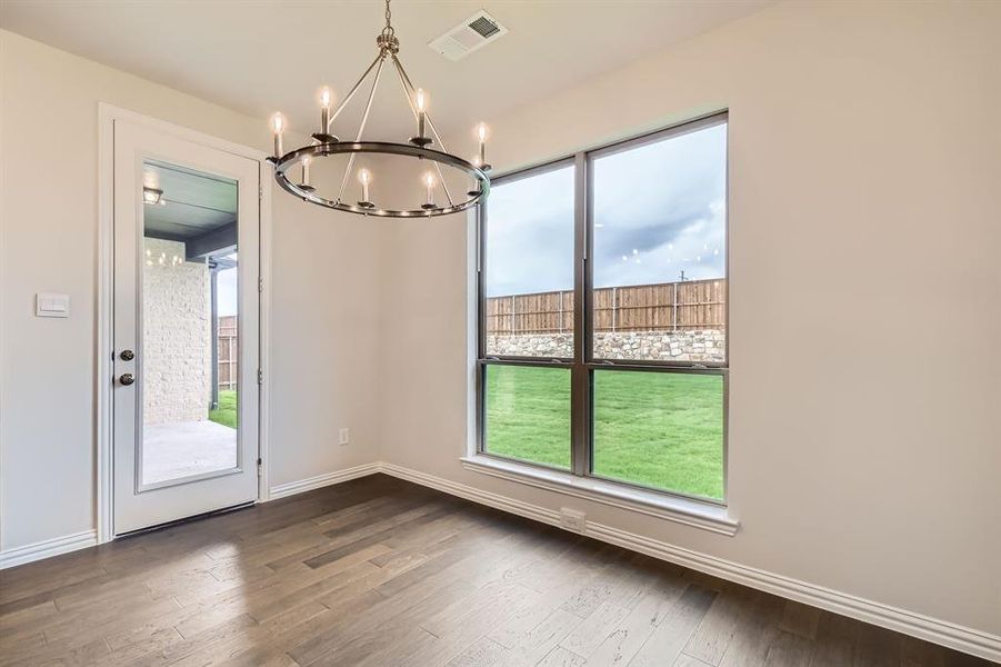 Unfurnished dining area with dark wood-type flooring, a healthy amount of sunlight, and a notable chandelier