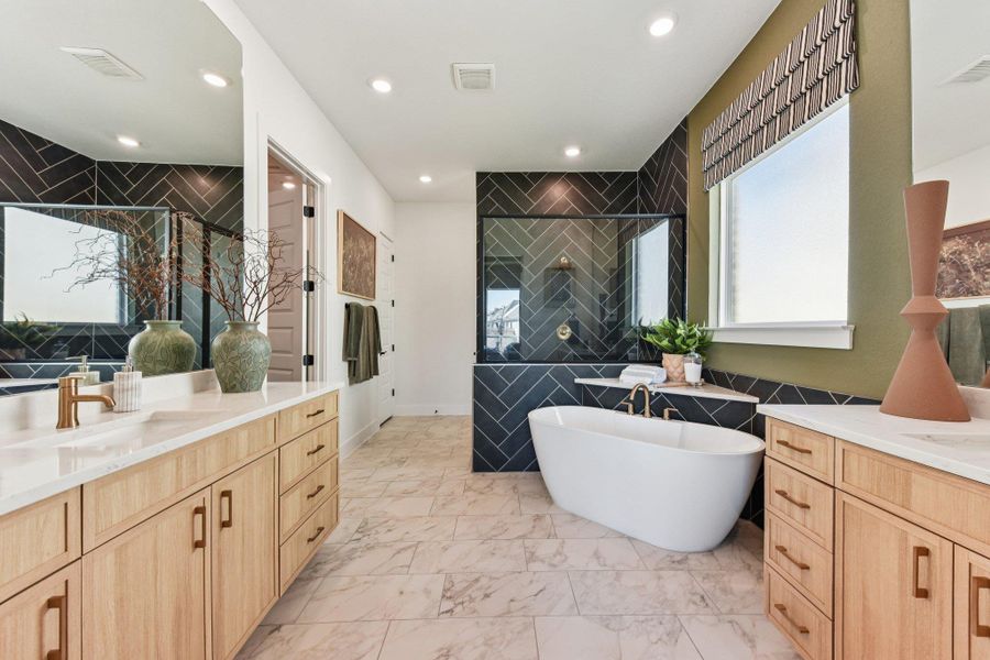 Geometric wall tile and marble floors frame a modern freestanding tub and double vanity.