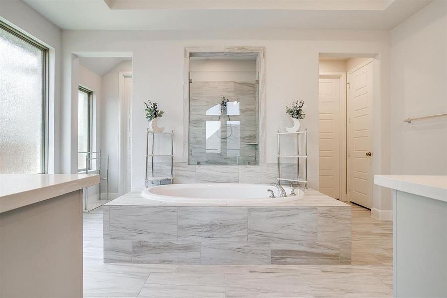 Full bathroom featuring a garden tub, vanity, and marble finish flooring Full bathroom featuring a garden tub, vanity, and marble finish flooring