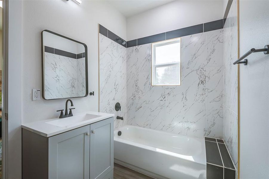 Bathroom featuring hardwood / wood-style floors, tiled shower / bath combo, and vanity