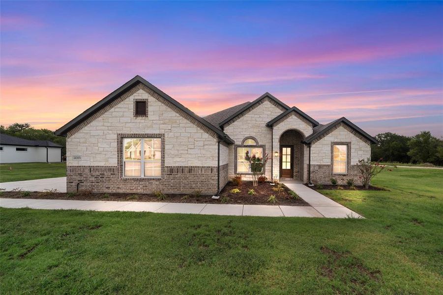 French provincial home featuring a front yard, stone siding, and brick siding