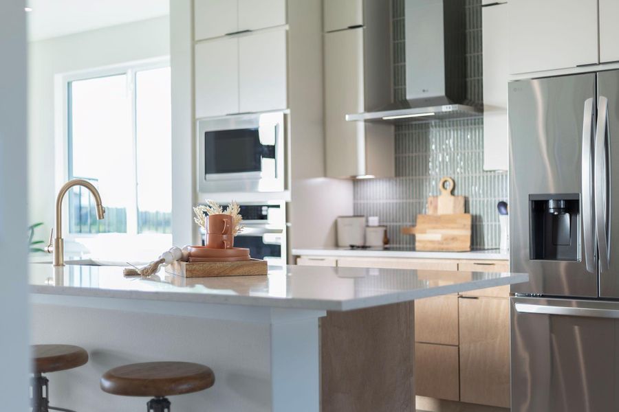 Kitchen with modern cabinets, stainless steel refrigerator with ice dispenser, a breakfast bar area, and built in microwave