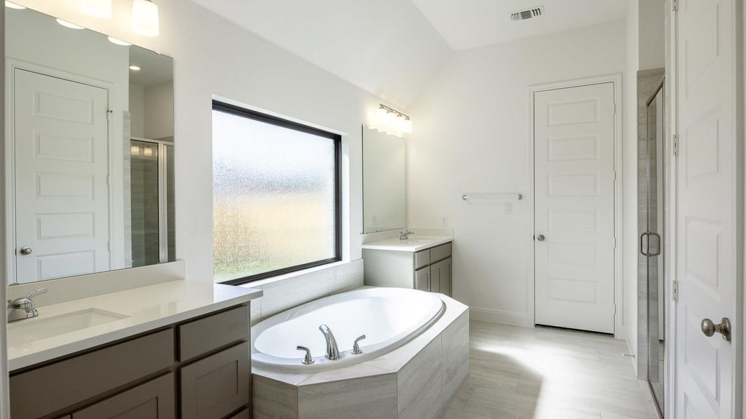Full bathroom featuring two vanities, a stall shower, and a bath Full bathroom featuring two vanities, a stall shower, and a bath