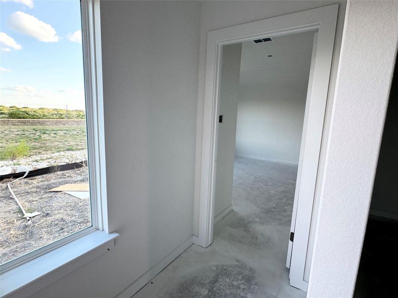 Hallway featuring unfinished concrete floors and healthy amount of natural light Hallway featuring unfinished concrete floors and healthy amount of natural light