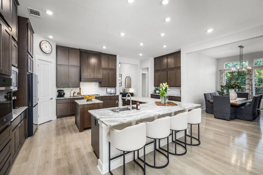 An inviting open-concept kitchen features a spacious island with bar seating and light-colored hardwood flooring.