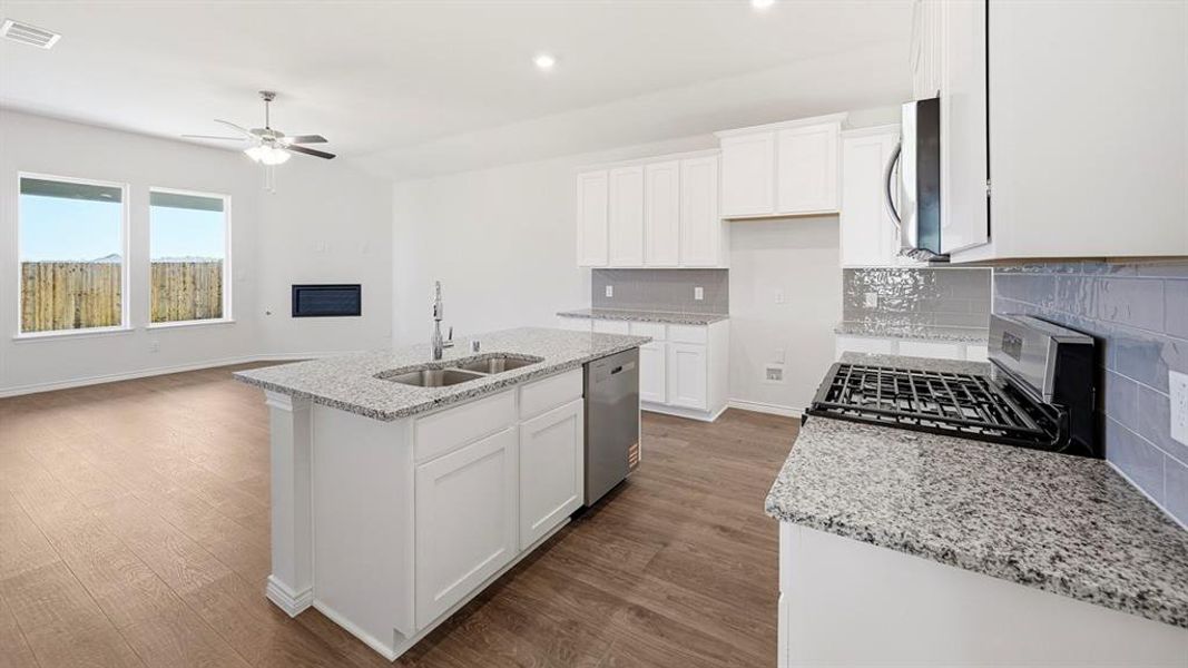 Kitchen with decorative backsplash, white cabinetry, light stone countertops, stainless steel appliances, and recessed lighting