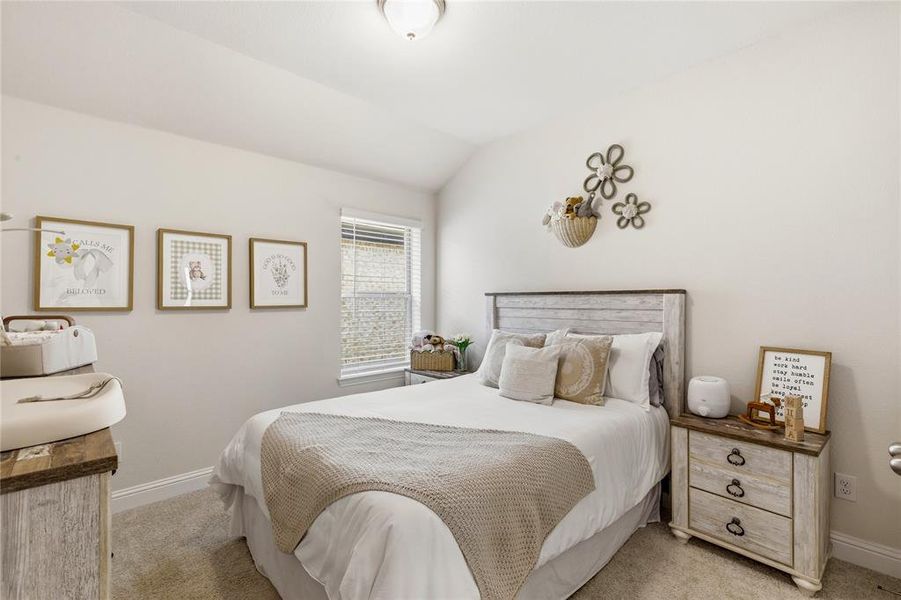 Bedroom featuring a vaulted ceiling and window with blinds