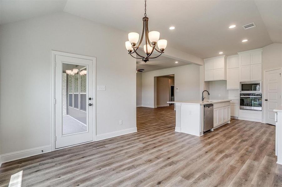 Kitchen featuring light hardwood / wood-style flooring, white cabinetry, an island with sink, and stainless steel appliances