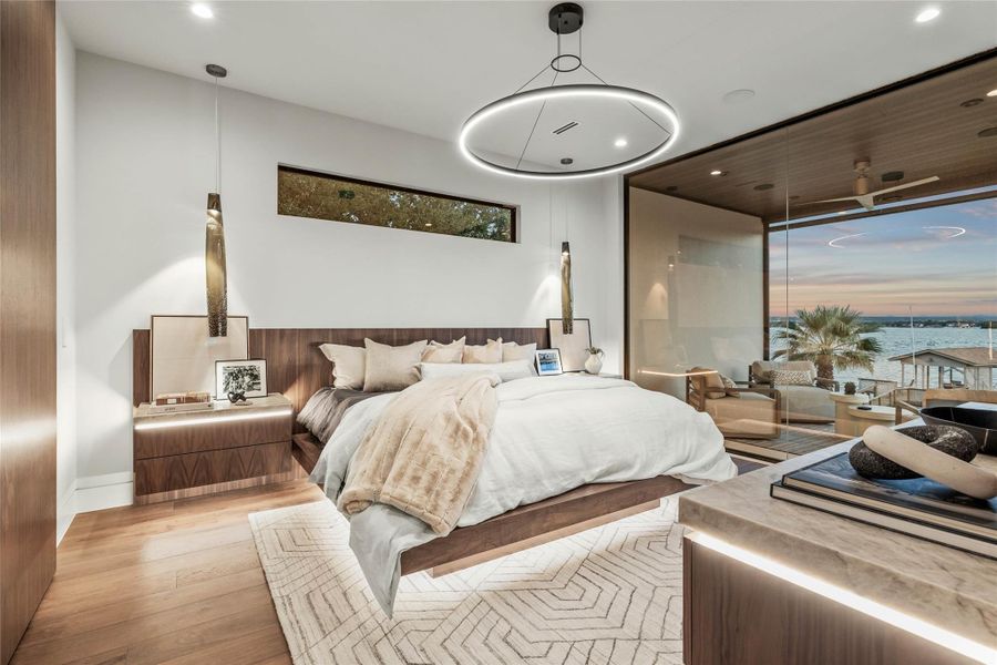 Hardwood flooring extends throughout this space featuring built-in wood-finish cabinetry, a large panoramic window wall, and recessed and pendant lighting fixtures