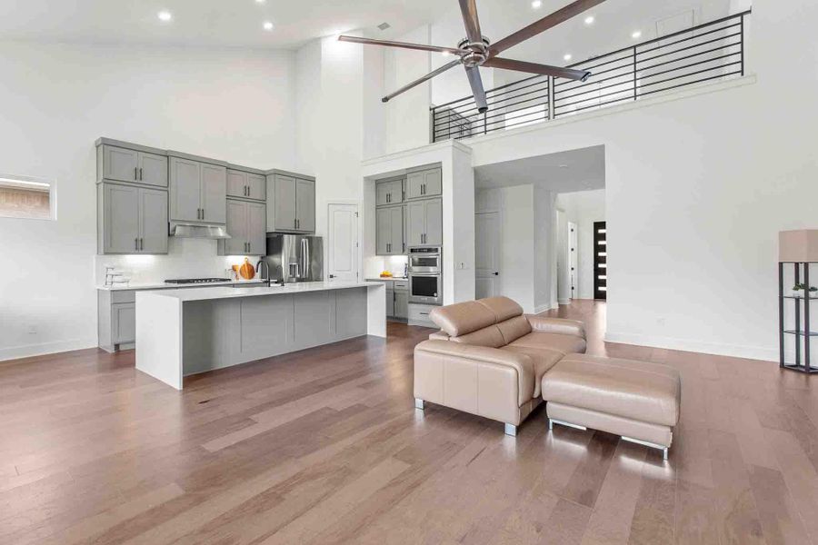 Open-concept living space with wood-finish flooring, a contemporary kitchen, and soaring ceilings