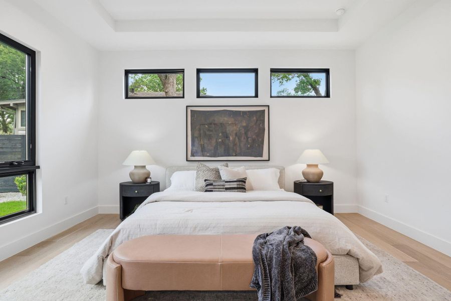 Spacious room featuring light wood-finish flooring, a tray ceiling, and recessed lighting