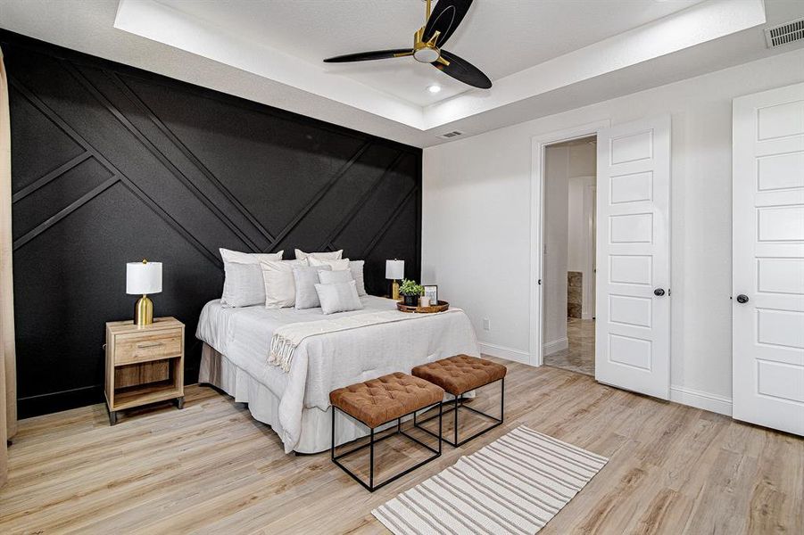 Bedroom featuring a tray ceiling, light wood-style floors, ceiling fan, and recessed lighting