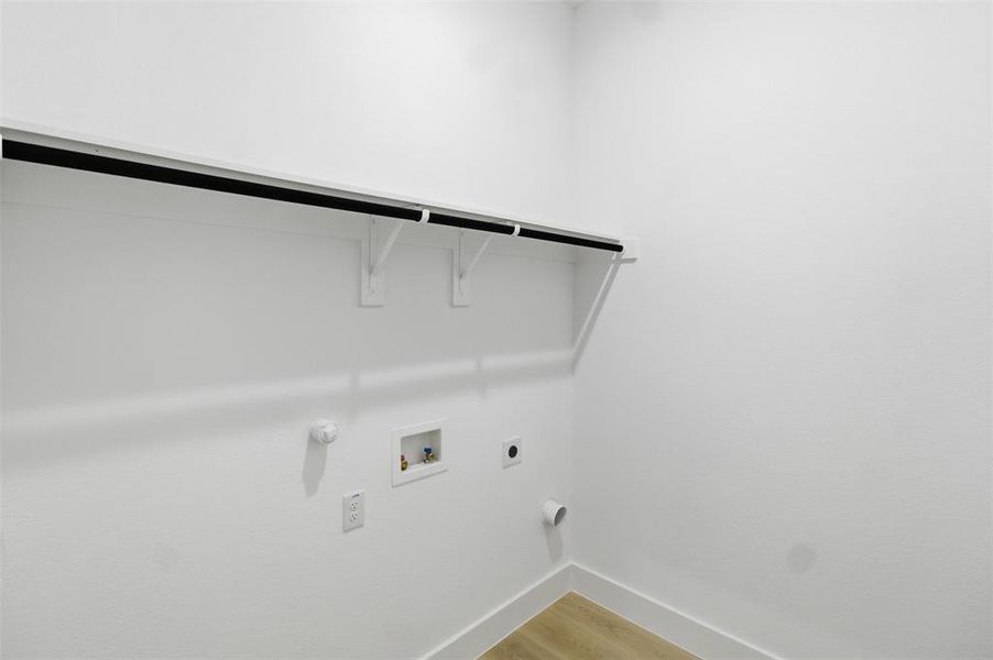 Washroom featuring light wood-style flooring, hookup for a gas dryer, hookup for a washing machine, and electric dryer hookup