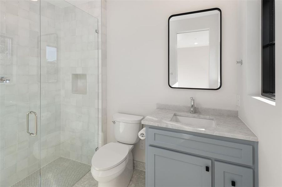 Bathroom featuring tile patterned floors, vanity, toilet, and walk in shower