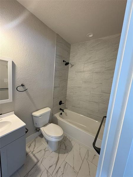 Bathroom featuring a tiled shower surround, integrated bathtub, and white vanity with a single basin Bathroom featuring a tiled shower surround, integrated bathtub, and white vanity with a single basin