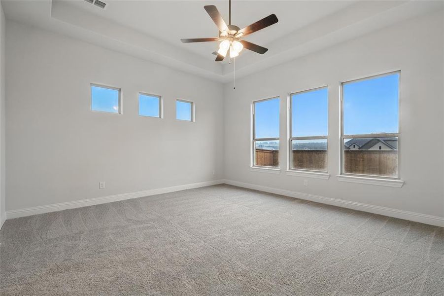 Unfurnished room featuring carpet, ceiling fan, baseboards, and a raised ceiling Unfurnished room featuring carpet, ceiling fan, baseboards, and a raised ceiling