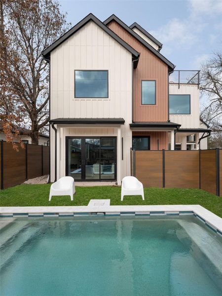 Rear view of house featuring a fenced backyard, board and batten siding, and a balcony