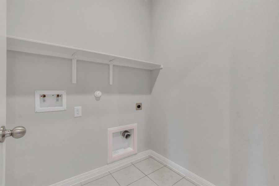 A well-appointed laundry space features a convenient utility shelf and durable tile flooring.
