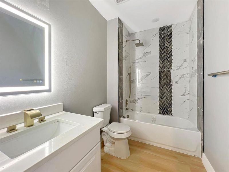 Full bathroom featuring vanity, toilet, wood-type flooring, and tiled shower / bath