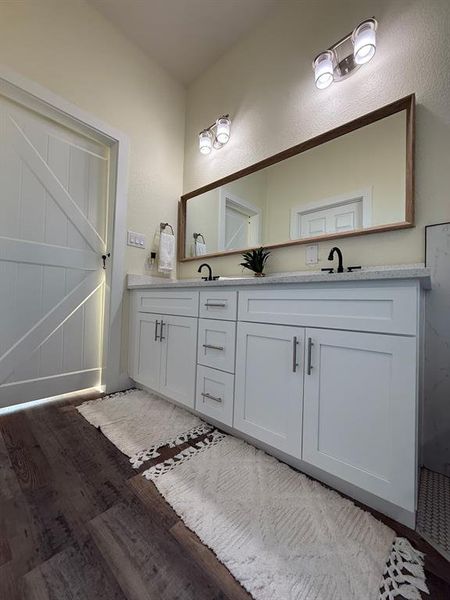 Master bathroom and double sink with white quartz, white shaker cabinets with self closing latches and hardware.  White barn door from the master bedroom.