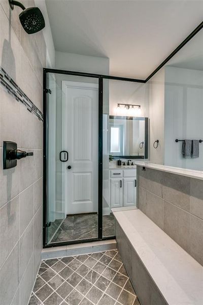 Bathroom with tile walls, walk in shower, vanity, and tile floors