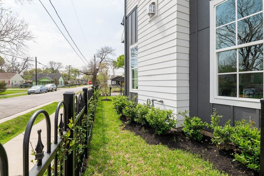 Green space wraps around the side of home to a yard in back that is fenced in.