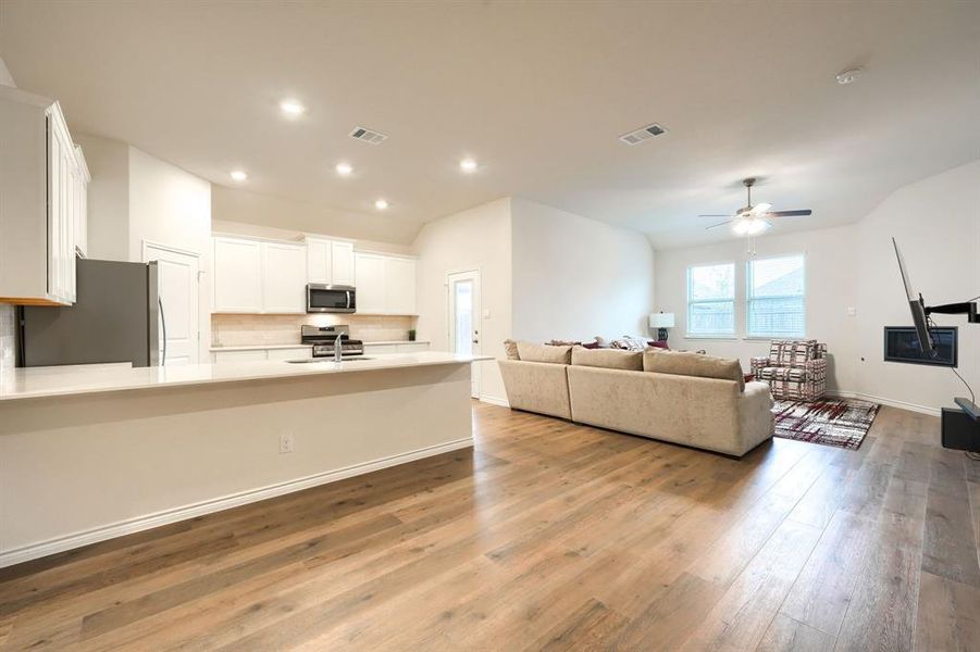 Living area with ceiling fan, light wood-style flooring, recessed lighting, and vaulted ceiling Living area with ceiling fan, light wood-style flooring, recessed lighting, and vaulted ceiling