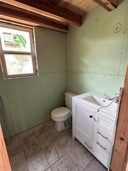 A partially finished bathroom awaiting final touches, featuring a window and tiled flooring.