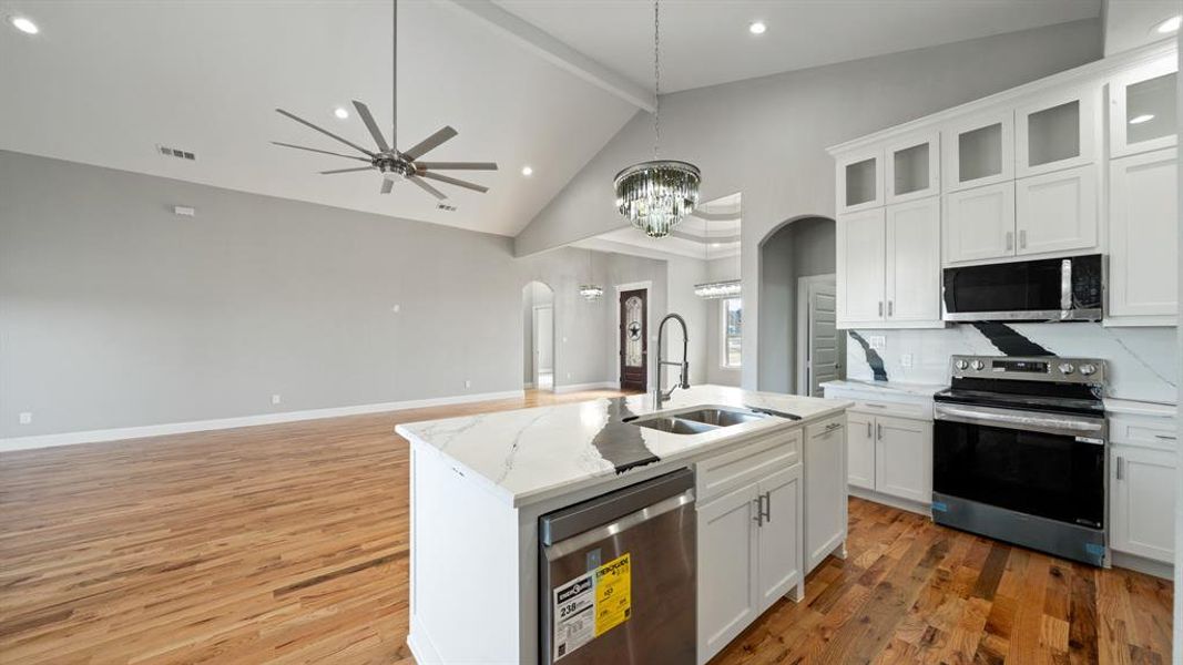 Kitchen featuring arched walkways, light wood finished floors, visible vents, appliances with stainless steel finishes, and a sink