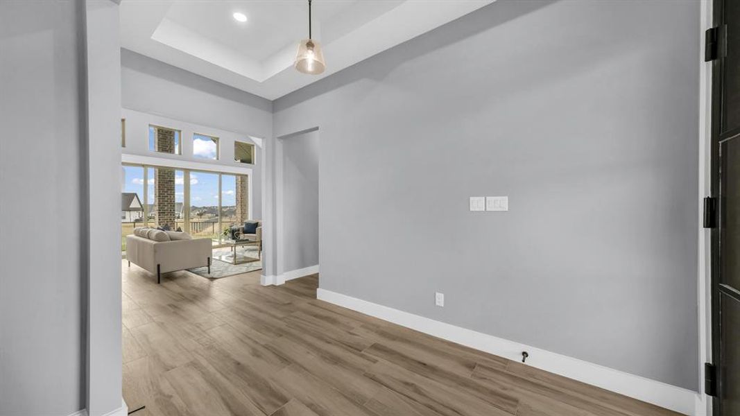 Unfurnished room with a raised ceiling, wood finished floors, and a high ceiling