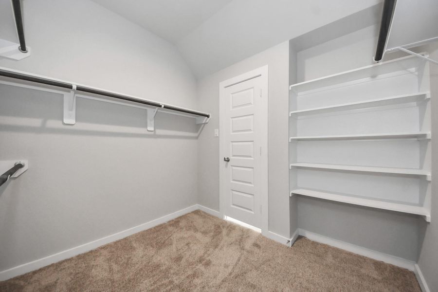 Walk-in closet that epitomizes luxury and practicality. This generously sized space features built-in shelving, offering abundant room for impeccable organization. High ceilings and recessed lighting create a bright and welcoming ambiance. Sample photo of completed home with similar floor plan. Actual colors and selections may vary.