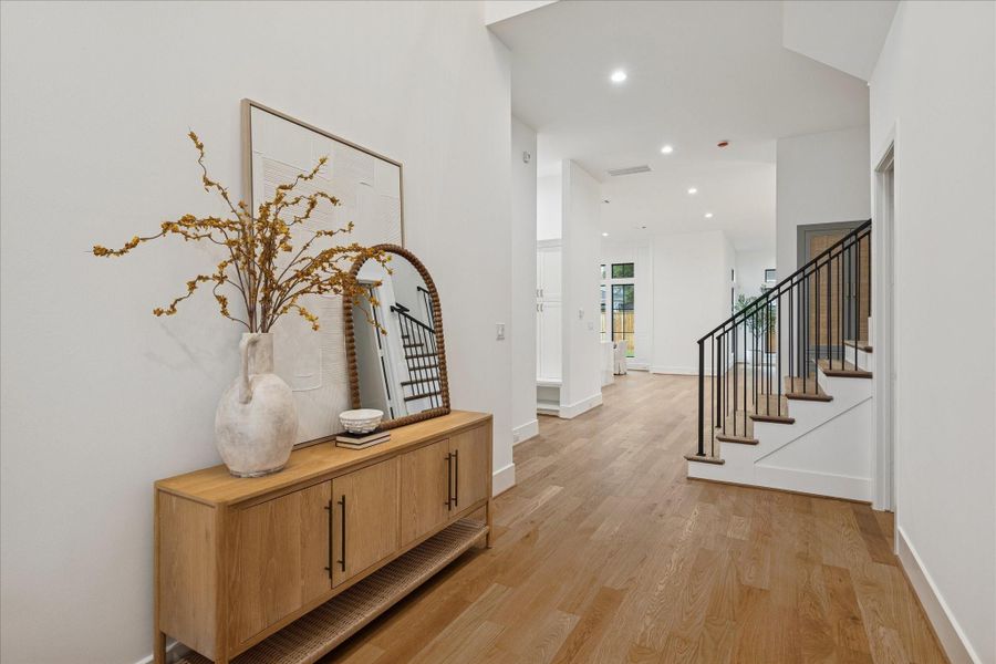 A soaring two-story foyer sets the tone with architectural symmetry, abundant light, and the elevated craftsmanship signature to Arch Angelo Homes. Wide-plank hardwoods flow throughout, complemented by 8 foot doors, Emtek hardware, and an iron-baluster staircase with oak treads. Pella windows bring in natural brightness, while the upper gallery landing introduces scale and spatial drama. Clean lines and refined millwork create a striking yet timeless welcome. *Previous Project*