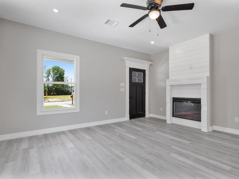 Unfurnished living room with a ceiling fan, light wood-type flooring, baseboards, a fireplace, and recessed lighting