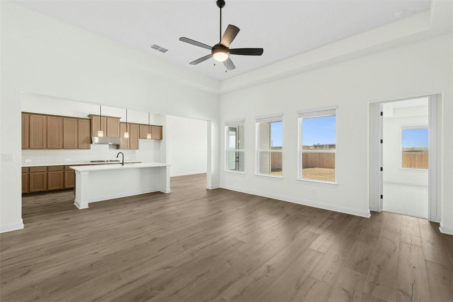 Unfurnished living room with ceiling fan, dark wood finished floors, and a tray ceiling
