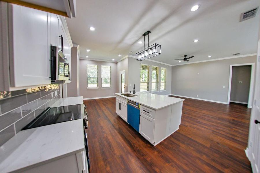 Kitchen featuring range with electric cooktop, white cabinetry, ornamental molding, pendant lighting, and open floor plan Kitchen featuring range with electric cooktop, white cabinetry, ornamental molding, pendant lighting, and open floor plan
