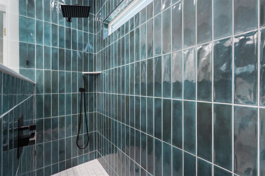 Shower featuring floor-to-ceiling teal subway tile, matte black fixtures, a built-in shower niche, and a contrasting light-toned shower pan