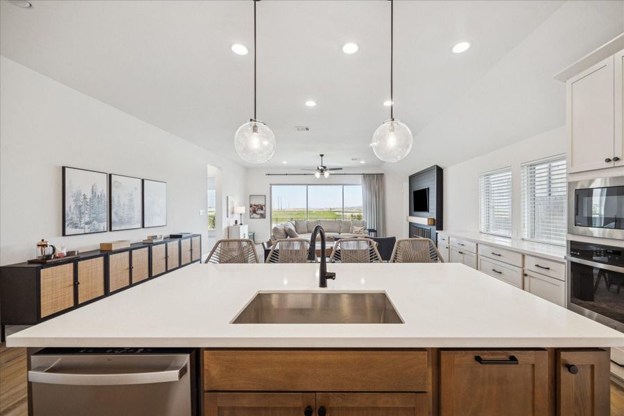 A seamless view with large sliding glass doors that open up to a covered patio and a lake view.