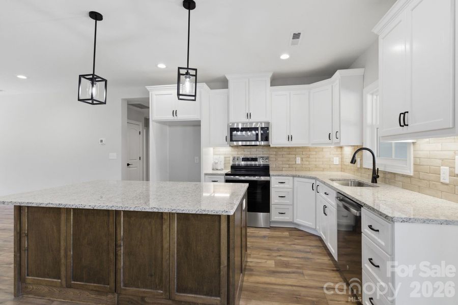 Two-tone custom kitchen cabinetry paired with a classic subway tile that complements the kitchen and overall color palette of the home