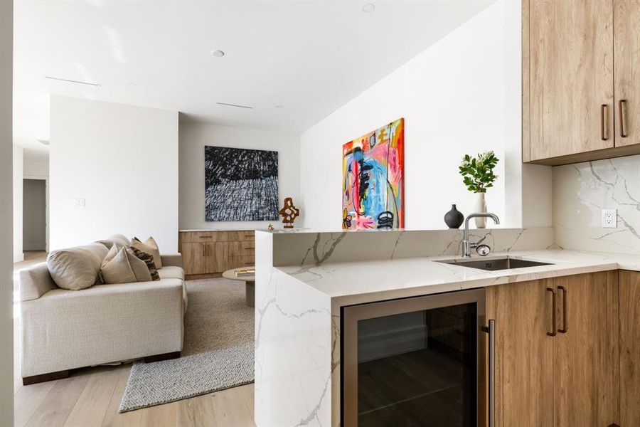 Bar with light stone countertops, beverage cooler, brown cabinets, light wood finished floors, and modern cabinets Bar with light stone countertops, beverage cooler, brown cabinets, light wood finished floors, and modern cabinets