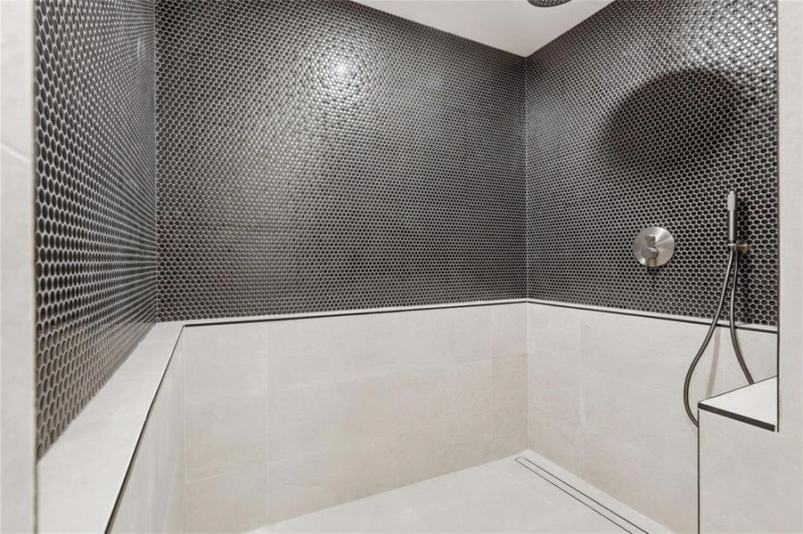 Shower enclosure featuring dark penny tile accent wall, light-toned large format ceramic wall tiles, recessed linear drain, brushed nickel shower controls, and a handheld showerhead