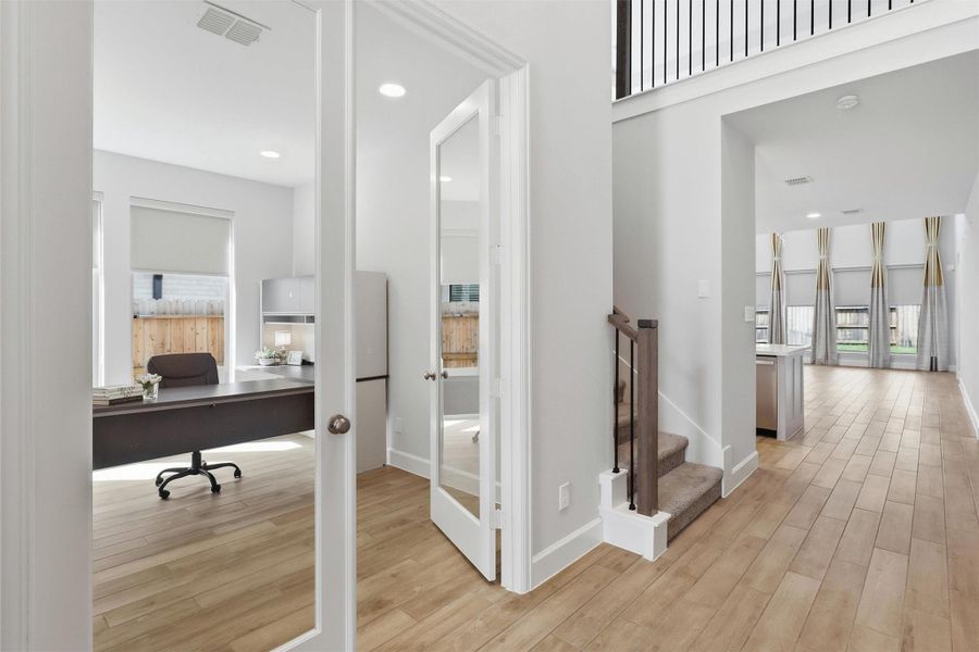 Just off the entry, elegant glass French doors open to a dedicated home office, while the thoughtfully designed layout leads effortlessly into the expansive open-concept living spaces beyond. The staircase provides convenient access to the upstairs game room and additional living area.