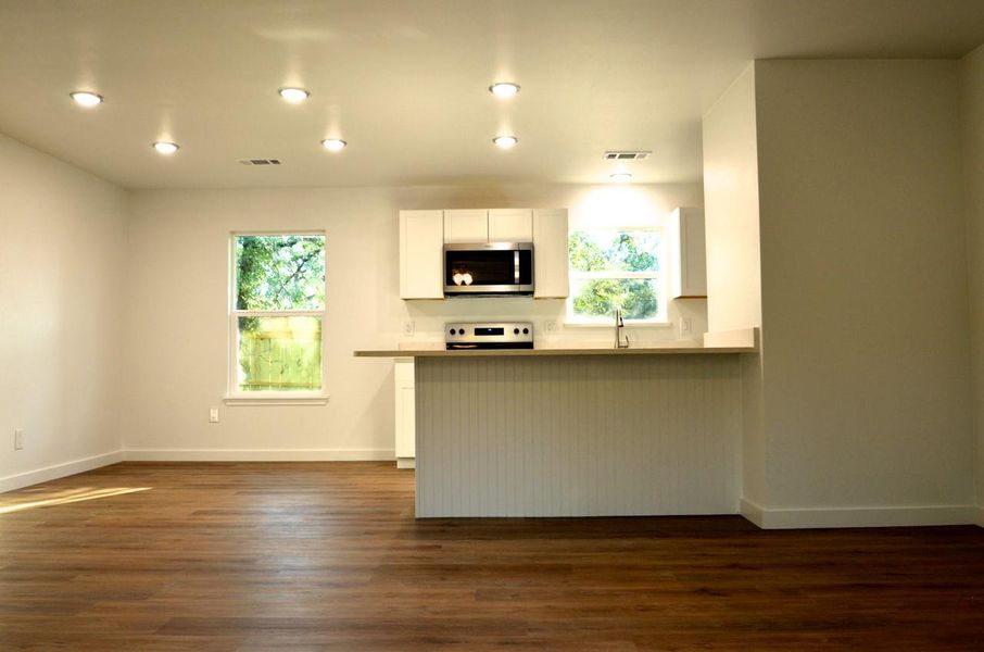 Kitchen featuring white cabinets, stainless steel microwave, dark wood finished floors, plenty of natural light, and recessed lighting