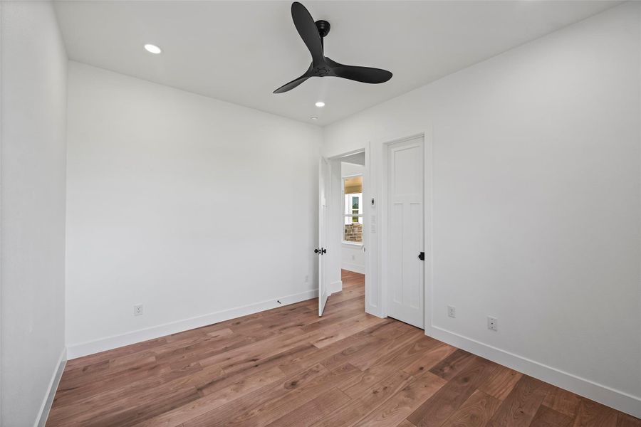 Charming second bedroom with sleek ceiling fan, warm LVP flooring, and ample natural light. Perfect for guests or a cozy home office.