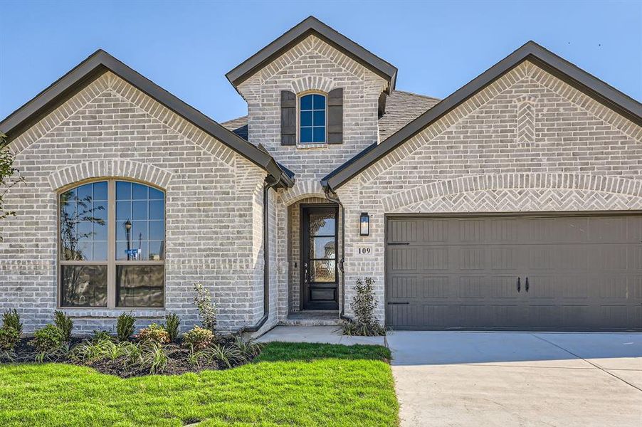 View of front of property featuring a front lawn and a garage